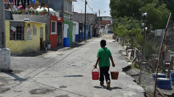 Un niño carga cubetas con agua para llevar a su casa en un barrio de Iztapalapa, alcaldía de la Ciudad de México que enfrenta constantes problemas de acceso al agua - Sputnik Mundo