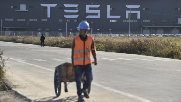 Un trabajador camina por una carretera junto a la nueva fábrica de Tesla construida en Shanghái, China  - Sputnik Mundo