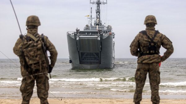 Un par de soldados mira hacia un buque de guerra de la Armada polaca durante maniobras militares de soldados polacos y de la OTAN en el norte de Polonia, el 17 de abril de 2023. - Sputnik Mundo
