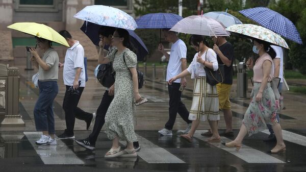 Residentes se cubren con paraguas mientras un aguacero empapa Pekín, el 29 de julio de 2023 - Sputnik Mundo