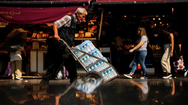 Un hombre empuja un carrito con botellas de agua en un caluroso día de verano, en Estambul, Turquía - Sputnik Mundo