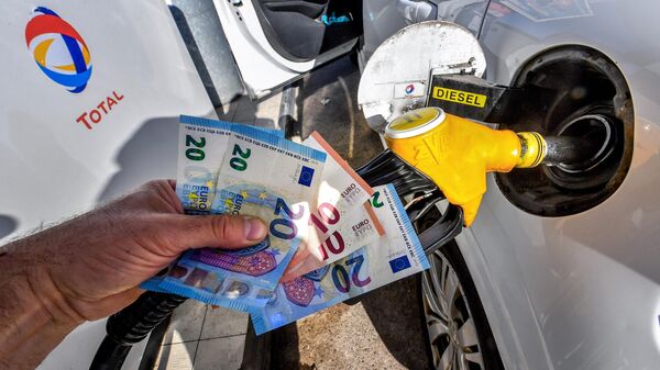 Un hombre sostiene en su mano billetes de euro en una gasolinera en Francia - Sputnik Mundo
