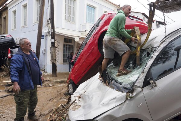 Una excavadora intenta sacar un coche dañado del barro tras las lluvias en el pueblo de Milina, Grecia. - Sputnik Mundo