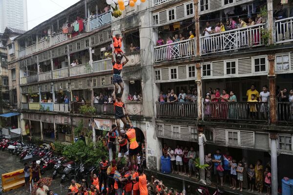 Varias personas forman una pirámide humana para alcanzar una olla de barro mientras celebran el festival Janmashtami en Bombay, la India. - Sputnik Mundo