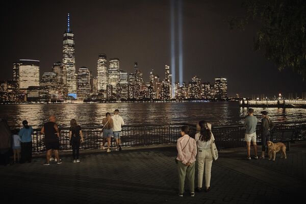 Personas observan el tributo de luz en el cielo de Nueva York desde el otro lado del río Hudson en el 22º aniversario de los atentados terroristas del 11-S. - Sputnik Mundo