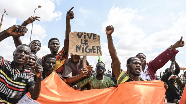 Partidarios del Consejo Nacional para la Salvaguarda de la Patria (CNSP) de Níger agitan una pancarta mientras se manifiestan en Niamey el 27 de agosto de 2023  - Sputnik Mundo