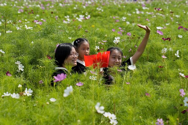 Una mujer y sus hijas en un campo de flores en la ciudad china de Hangzhou durante la celebración del 74 aniversario de la fundación de China. - Sputnik Mundo