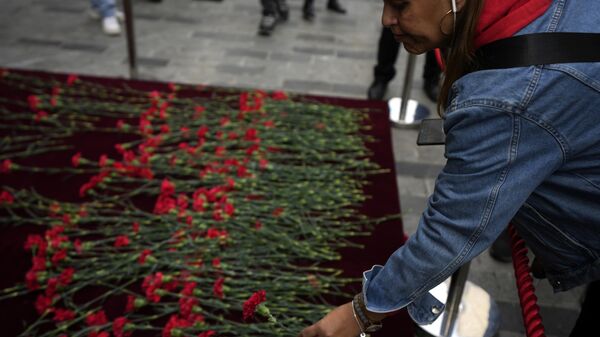 Varias personas colocan flores sobre un monumento conmemorativo colocado en el lugar de la explosión en la popular avenida peatonal Istiklal de Estambul, en Estambul - Sputnik Mundo