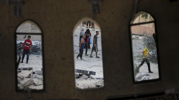 Un grupo de personas frente a una mezquita destruida por un ataque aéreo israelí en Jan Younis, Franja de Gaza, el domingo 8 de octubre de 2023. - Sputnik Mundo