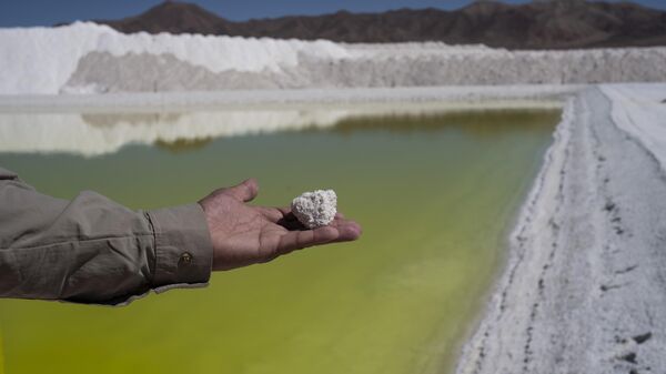 Trabalhador da mina de lítio Albemarle mostra um pedaço de sal perto de uma piscina de salmoura altamente concentrada em lítio no deserto do Atacama, no Chile, segunda-feira, 17 de abril de 2023 - Sputnik Mundo