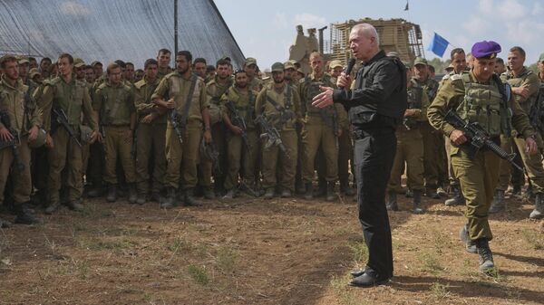 Yoav Gallant, el ministro de Defensa de Israel, con chaleco protector, habla con soldados israelíes en una zona de concentración cerca de la frontera con la Franja de Gaza, el 19 de octubre de 2023 - Sputnik Mundo