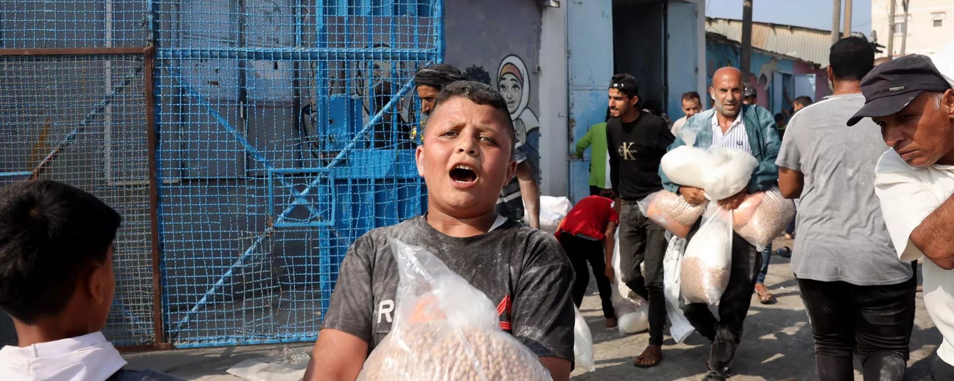 Un niño palestino sostiene una bolsa de garbanzos recibida de un centro humanitario de la ONU en Deir al-Balah - Sputnik Mundo, 1920, 31.10.2023