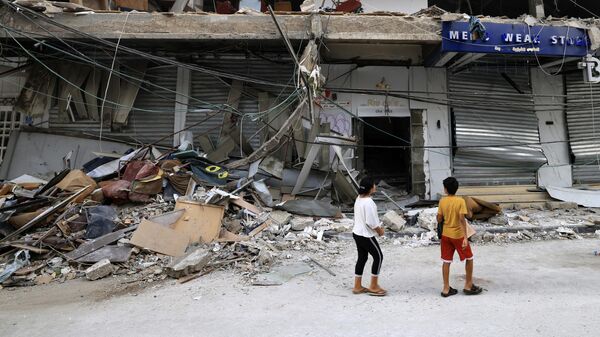Dos niños observan un edificio destruido por los bombardeos israelíes en la Franja de Gaza - Sputnik Mundo