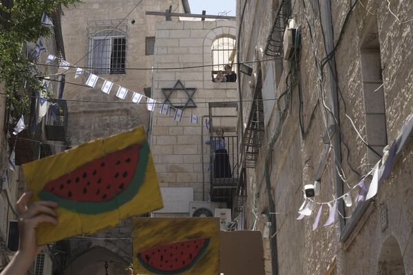 Niñas judías observan a israelíes y palestinos que sostienen imágenes de sandías, un símbolo palestino, mientras protestan por el inminente desalojo de Nora y Mustafa Sub Laban, el 16 de junio de 2023. - Sputnik Mundo