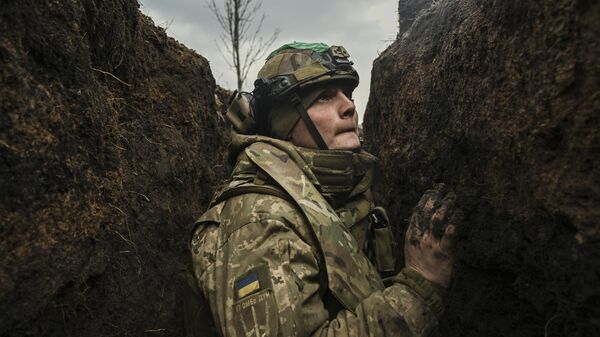 Un militar ucraniano se refugia en una trinchera durante un bombardeo cerca de la ciudad de Artiómovsk (Bajmut), el 8 de marzo de 2023  - Sputnik Mundo