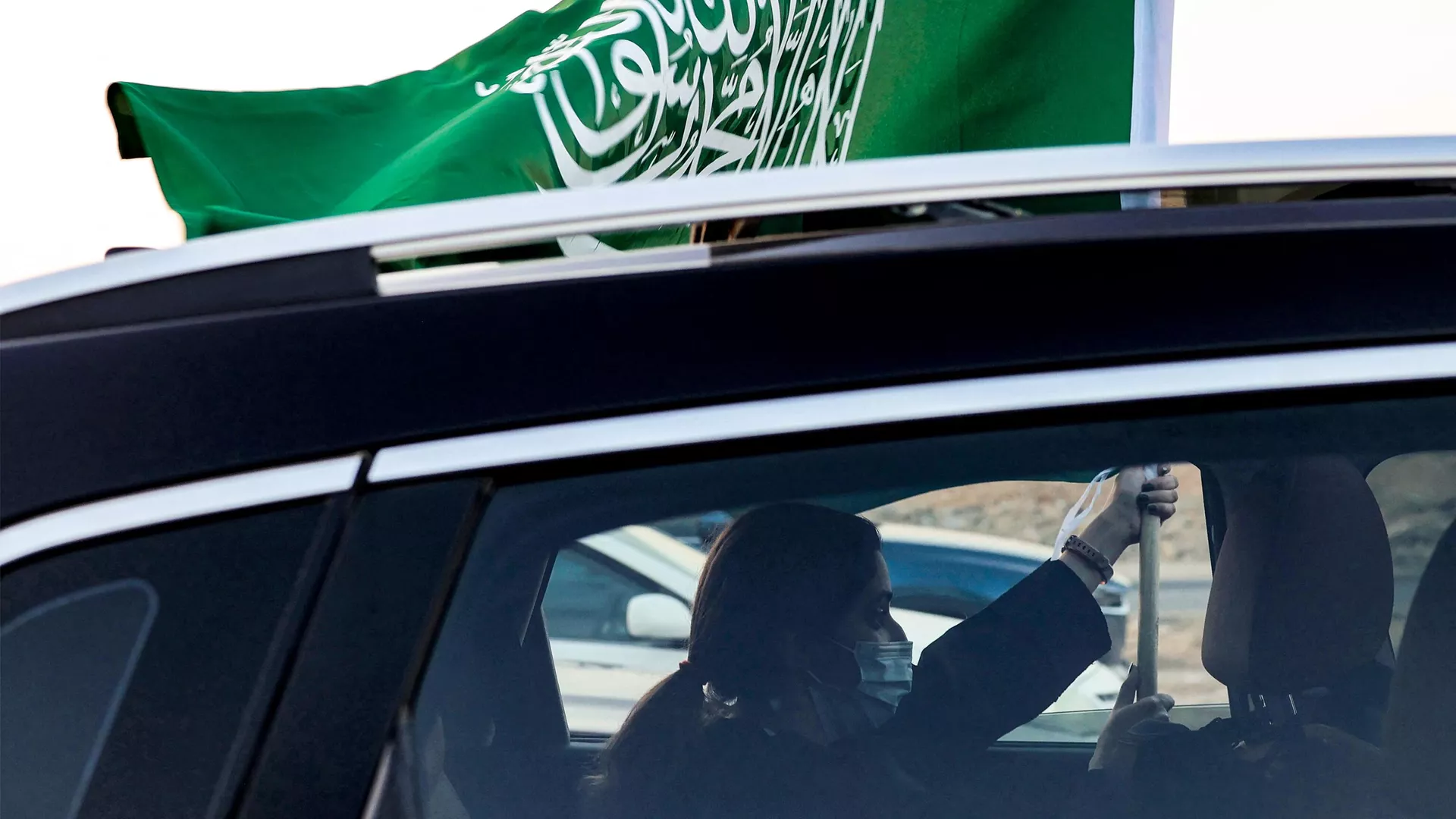 Una mujer sostiene una bandera nacional de Arabia Saudita desde la ventana de un vehículo mientras asiste a un espectáculo aéreo que marca las celebraciones del 93º Día Nacional de Arabia Saudí en Riad el 23 de septiembre de 2023.  - Sputnik Mundo, 1920, 23.12.2023