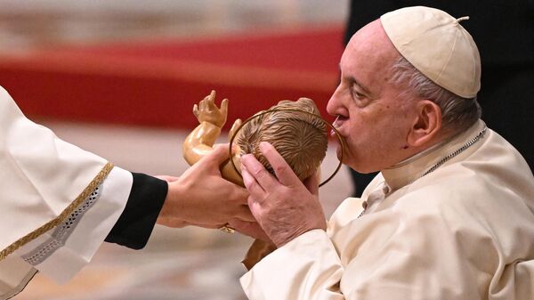 El papa Francisco besa una estatuilla del Niño Jesús mientras asiste a la misa de Nochebuena en la Basílica de San Pedro del Vaticano. - Sputnik Mundo