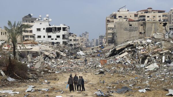 Palestinos caminan junto al edificio destruido en el bombardeo israelí de la Franja de Gaza  - Sputnik Mundo