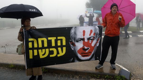 Dos personas se manifiestan en contra de las acciones del primer ministro israelí Benjamín Netanyahu el 23 de enero de 2024 en Moshav Elifelet, al norte de Israel - Sputnik Mundo