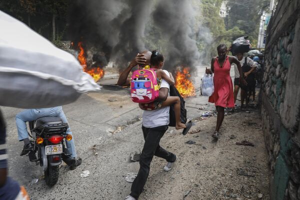 Personas se apresuran a abandonar un barrio asolado por las protestas antigubernamentales en Puerto Príncipe, Haití. - Sputnik Mundo