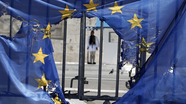 Un guardia presidencial griego permanece enmarcado por los restos de una bandera de la Unión Europea, medio quemada por manifestantes en Atenas, el 1 de mayo de 2013 - Sputnik Mundo