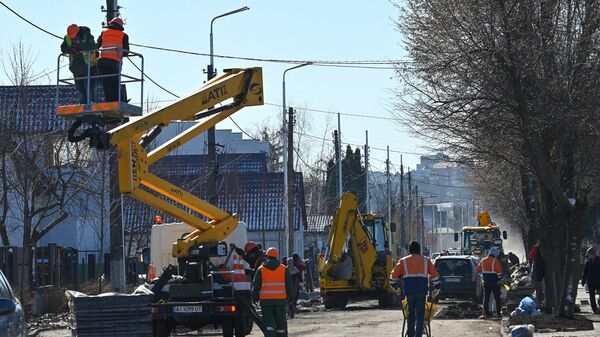 Obreros realizan trabajos de reparación en la ciudad de Bucha, al noroeste de Kiev, el 30 de marzo de 2023  - Sputnik Mundo
