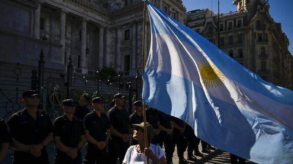 Una mujer sostiene una bandera argentina frente a una línea de policías durante una huelga nacional contra el Gobierno de Javier Milei en Buenos Aires el 24 de enero de 2024  - Sputnik Mundo