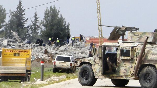 Un vehículo del Ejército libanés bloquea una carretera que conduce a un almacén destruido, al fondo, que fue atacado por la aviación israelí, bastión de Hezbolá, Líbano, el 26 de febrero de 2024  - Sputnik Mundo