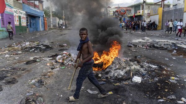 Un hombre camina entre barricadas en la capital de Haití, Puerto Príncipe, en medio de la violencia que azota al país - Sputnik Mundo