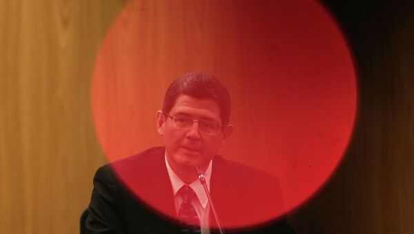 Brazil's Finance Minister Joaquim Levy, pictured through a red LED light of a camera, reacts during a news conference at Brazil's Central Bank in Brasilia January 5, 2015. - Sputnik Mundo