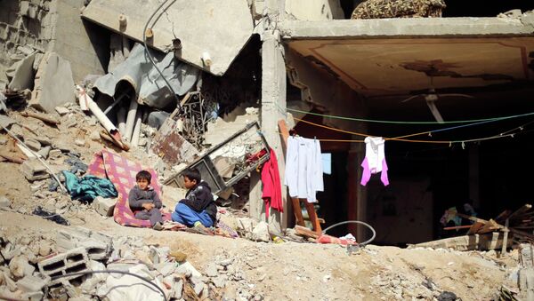 Palestinian boys sit outside their damaged house - Sputnik Mundo