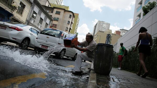 A man pours excess water on to the road after filling up his barrel in Sao Paulo February 3, 2015 - Sputnik Mundo