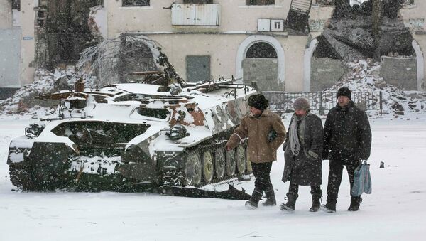 Locals walk past a destroyed Ukrainian army armoured personnel carrier in the town of Vuhlehirsk, about 10 km (6 miles) to the west of Debaltseve, February 16, 2015 - Sputnik Mundo