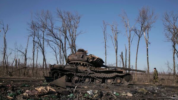 A fighter with the separatist self-proclaimed Donetsk People's Republic army looks at a destroyed Ukrainian army tank near the town of Debaltseve February 22, 2015 - Sputnik Mundo