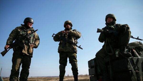 Members of the Ukrainian armed forces stand guard as a convoy of the Ukrainian armed forces including armoured personnel carriers, military vehicles and cannons prepare to move as they pull back from the Debaltseve region, in Blagodatne, eastern Ukraine, February 27, 2015 - Sputnik Mundo