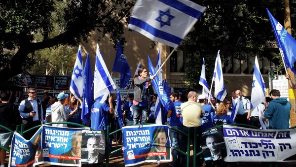 A woman waves an Israeli national flag outside a polling station in Tel Aviv March 17, 2015 - Sputnik Mundo