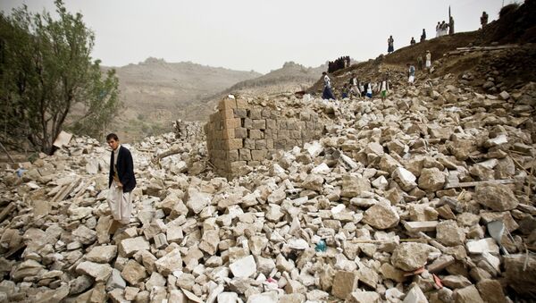 Yemenis stand amid the rubble of houses destroyed by Saudi-led airstrikes in a village near Sanaa - Sputnik Mundo