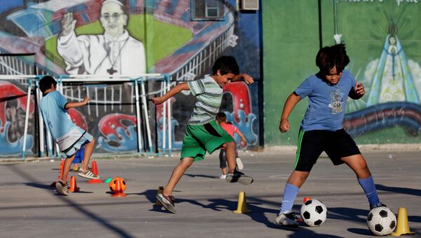 Children play soccer in front a mural of Pope Francis at the 1-11-14 slum in Buenos Aires, Argentina, Thursday, March 13, 2014 - Sputnik Mundo