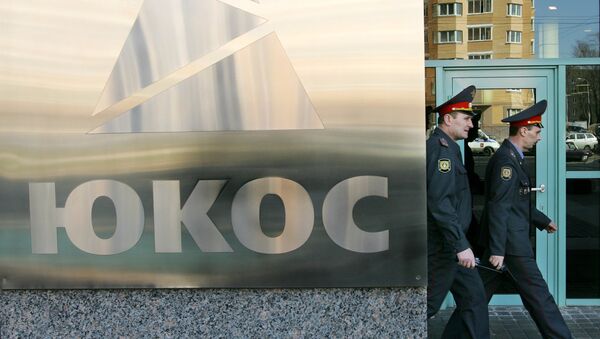Two policemen pass by the Yukos logo in Moscow during the auction of a package of assets of the stricken Yukos oil giant 27 March 2007. - Sputnik Mundo