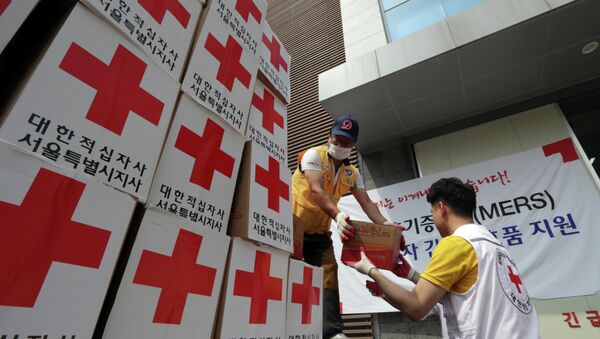Los miembros de la Cruz Roja de Corea del Sur descargan  un camión con ayuda para las personas que se sospecha de la infección - Sputnik Mundo