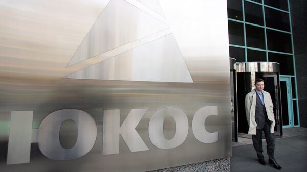A man passes by a Yukos logo at the headquarters of the oil company in Moscow after the latest auction for the sale of package of assets the stricken giant, 04 April 2007 - Sputnik Mundo