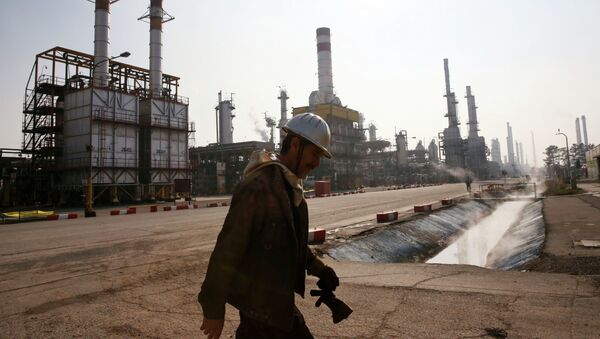 Trabajador petrolero iraní camina cerca una refinería de petróleo en Teherán, Irán - Sputnik Mundo