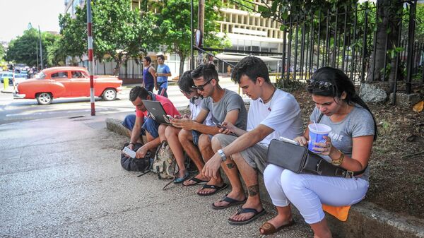 Cubans use their mobile devices to connect to internet via wi-fi in a street of Havana, on July 2, 2015 - Sputnik Mundo