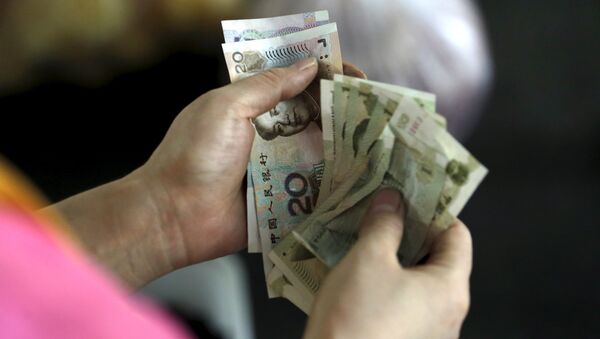 A customer counts Chinese Yuan notes at a market in Beijing, August 12, 2015 - Sputnik Mundo