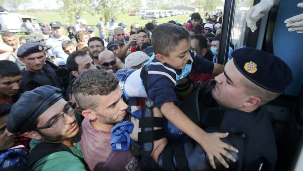 Policía croata ayuda a un niño de refugiado a subirse al autobús en Tovarnik, Croacia - Sputnik Mundo