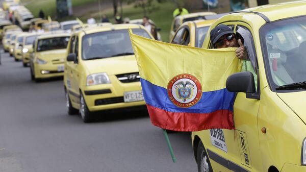A cab driver flashes a thumbs up and holds a Colombian national flags during a protest by taxi drivers against the Uber ride sharing service in Bogota, Colombia, Wednesday, July 29, 2015. - Sputnik Mundo