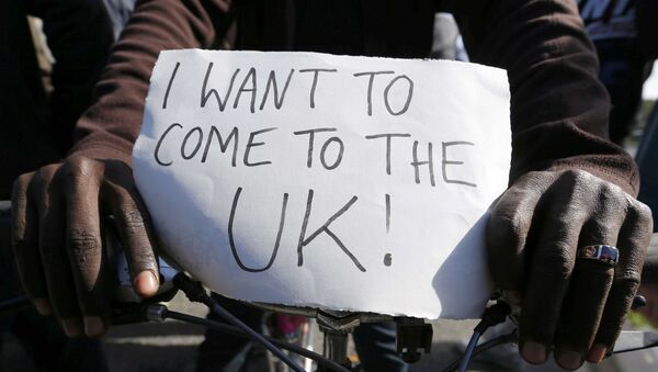 A migrant holds a placard which reads I want to come to the U.K. on his bicycle at the makeshift camp called The New Jungle in Calais, France, September 19, 2015. - Sputnik Mundo