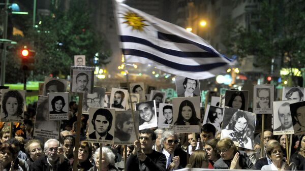 Demonstrators, one waving an Uruguayan flag, carry signs with images of people missing during Uruguay's 1973-85 dictatorship during a march in Montevideo, Uruguay - Sputnik Mundo