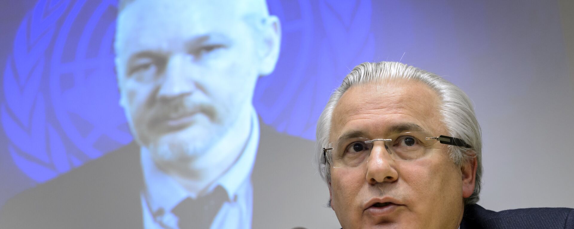 Spanish former judge Baltasar Garzon (R) speaks beneath WikiLeaks founder Julian Assange seen on a screen via web cast from the Ecuadorian Embassy in London during an event on the sideline of the United Nations (UN) Human Rights Council session on March 23, 2015 in Geneva. - Sputnik Mundo, 1920, 23.07.2021