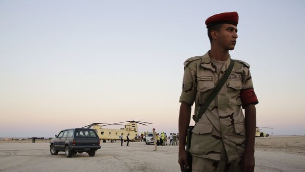 An Egyptian soldier stands guard as emergency workers unload bodies of victims from the crash of Airbus-321 - Sputnik Mundo